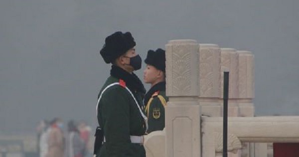 A paramilitary police officer wearing a mask stands with his colleague during the smog in Beijing