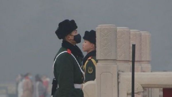 A paramilitary police officer wearing a mask stands with his colleague during the smog in Beijing