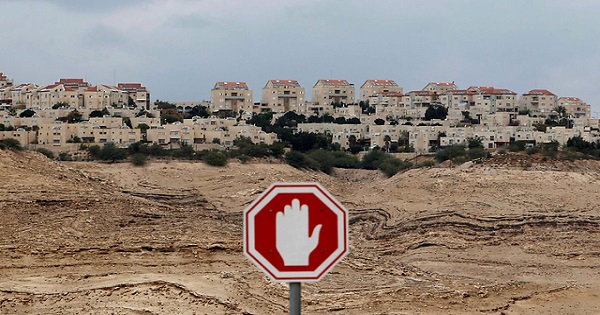 A sign suggests not to build any more settlements in the West Bank.