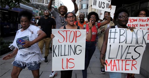 Black Lives Matter activists hold signs during a protest against police shootings of Black people in the United States.