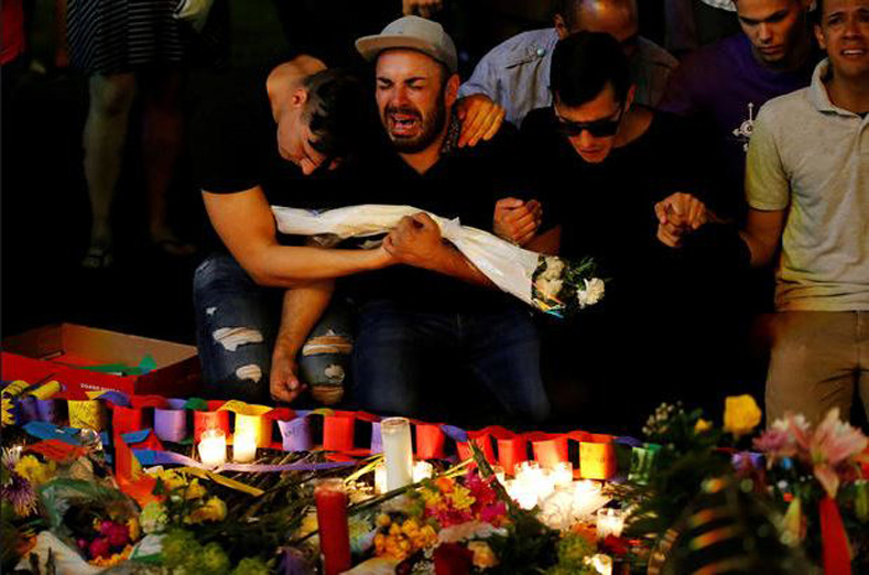 A man sits and cries after taking part in a candlelight memorial service the day after a mass shooting at the Pulse gay nightclub in Orlando, Florida, June 13, 2016.