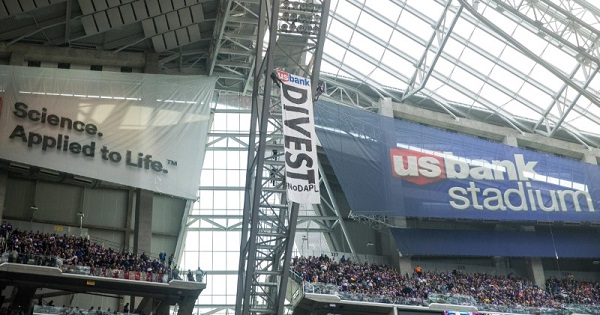Two protesters rappel from the rafters with a banner against the Dakota pipeline during an NFL game at U.S. Bank Stadium.