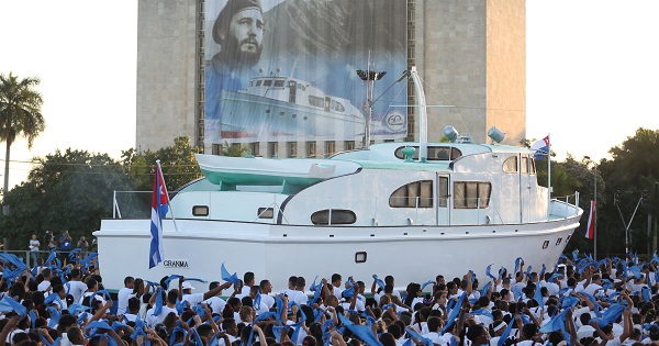 An image of late Cuban President Fidel Castro hangs on a building as a replica of the Granma yacht passes by during a march in Havana, Jan. 2, 2017.