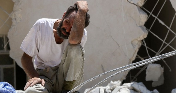 A man waits as Syrian civil defence workers look for survivors under the rubble of a collapsed building following reported air strikes.