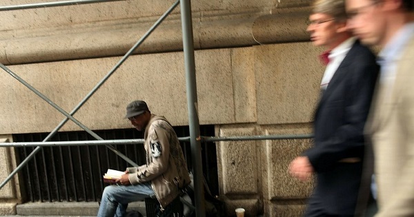 Businessmen walk by a homeless man on a New York street, Sep. 28, 2010.