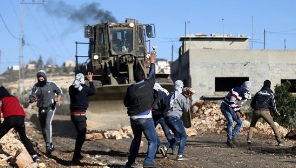 Palestinian protesters throw stones toward Israeli troops during clashes following a protest against the nearby Jewish settlement of Qadomem, in the West Bank.