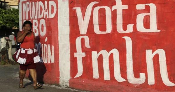 A woman walks by a mural urging Salvadorans to vote for the FMLN.
