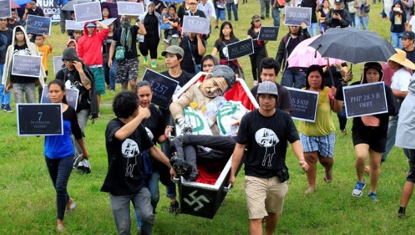 Anti-Marcos protesters carry an effigy of late dictator Ferdinand Marcos lying in a mock coffin during protest at a Luneta park, metro Manila.