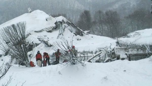 Members of Lazio's Alpine and Speleological Rescue Team stand in front of the Hotel Rigopiano in Farindola, central Italy, hit by an avalanche, Jan. 19, 201