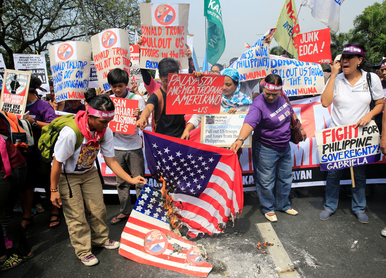 Protesters burn a U.S. flag and a mock flag with pictures of U.S. President-elect Donald Trump outside the U.S. embassy in metro Manila, Philippines, Jan. 20, 2017. 