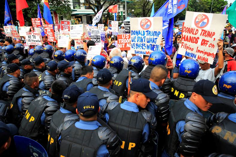 Anti-riot police block protesters holding placards against U.S. President-elect Donald Trump outside the U.S. embassy in metro Manila, Philippines, Jan. 20, 2017.