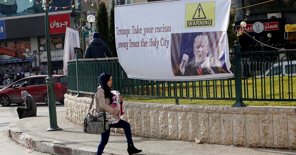 A Palestinian woman walks past a banner against U.S. President Donald Trump's promise to relocate the U.S. embassy to Jerusalem, in the West Bank city of Nablus.