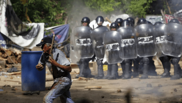 An injured protester flees as riot police use tear gas and batons to disperse a protest against the Tambor mine, Guatemala, May 23, 2014.