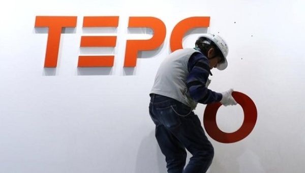 A worker puts up new logo of Tepco Holdings and Tokyo Electric Power Company Group on the wall at the Tepco headquarters in Tokyo.