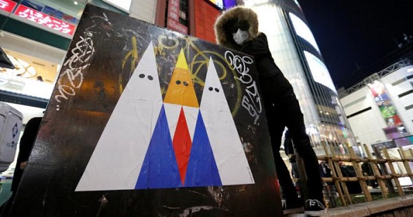 A Japanese graffiti artist known as 281 Antinuke poses with his sticker art depicting Donald Trump in Tokyo's Shibuya shopping district, Jan. 27, 2017.