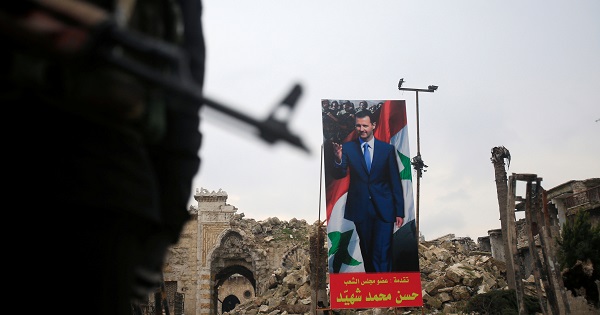 A Syrian Army soldier stands guard as a poster depicting Syria's President Bashar al-Assad is seen in the background in the Old City of Aleppo, Syria.