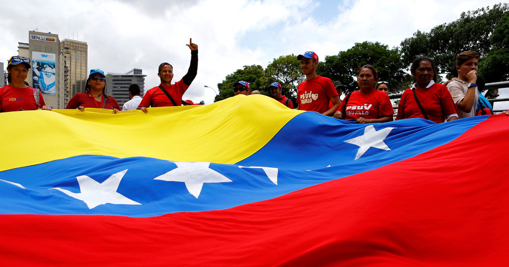 Pro-government supporters hold a Venezuelan flag during a rally of members of the education sector in Caracas, Venezuela June 14, 2016.