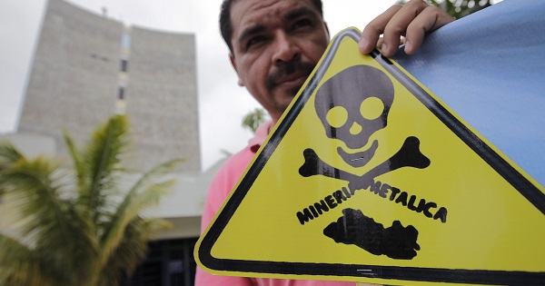 An demonstrator holds a sign condemning the toxicity of metals mining in El Salvador after an anti-mining coalition presented a proposal to block mining in 2013.