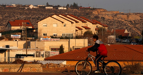 A boy rides his bicycle past houses in the Israeli settlements of Ofra, in the occupied West Bank, Feb. 6, 2017.