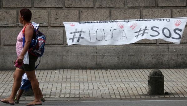 A woman walks past a sign to protest for better salaries for police officers, hung at the military police headquarters in Rio de Janeiro, Brazil, Feb. 14, 2017.