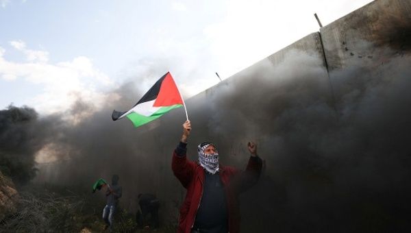 Protester holds a Palestinian flag during clashes with Israeli troops at a protest marking in the West Bank village of Bilin near Ramallah.