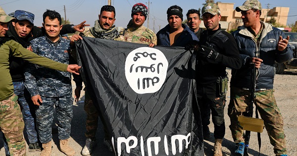Iraqi security forces members pose with a seized Islamic State flag after driving out its miitants from Mosul's airport south west Mosul.