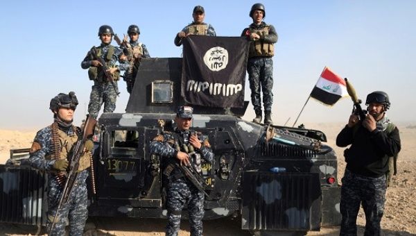 Iraqi federal police members pose with the Islamic State group flag along a street of Albu Saif south of Mosul.