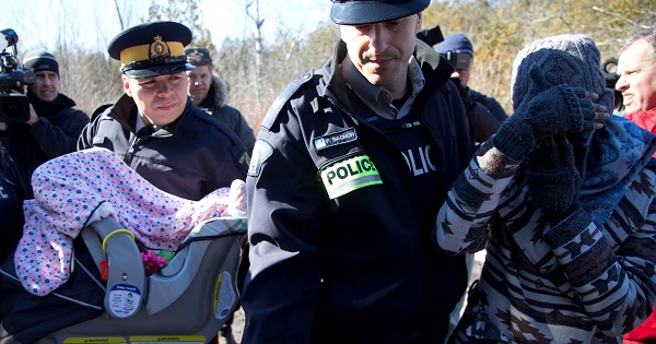 A mother and her child are taken into custody by RCMP officers after crossing U.S.-Canada border into Hemmingford, Quebec, Feb. 20, 2017.