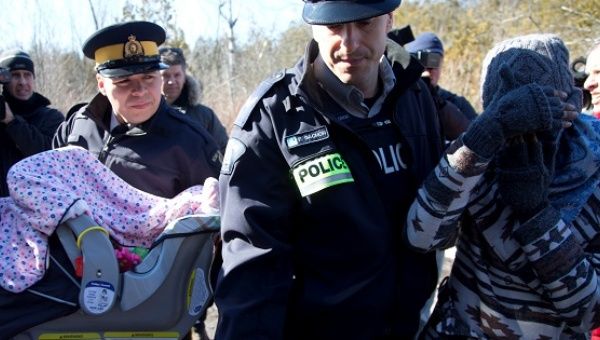 A mother and her child are taken into custody by RCMP officers after crossing U.S.-Canada border into Hemmingford, Quebec, Feb. 20, 2017.