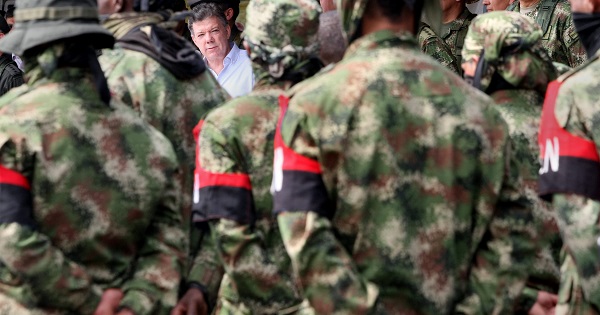 Colombian President Juan Manuel Santos looks on at a group of ELN soldiers who demobilized in 2013. The rebel army is now in peace talks.