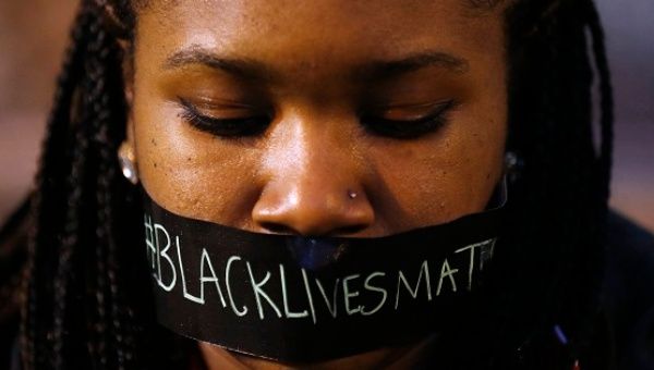 A demonstrator covers her mouth with the #BlackLivesMatter slogan to protest police brutality after the police killing of Michael Brown in Ferguson, Missouri.  