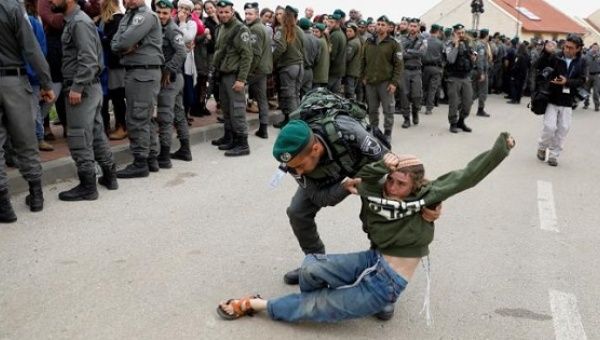 An Israeli border policeman removes a pro-settlement activist from a settlement in the occupied West Bank. 