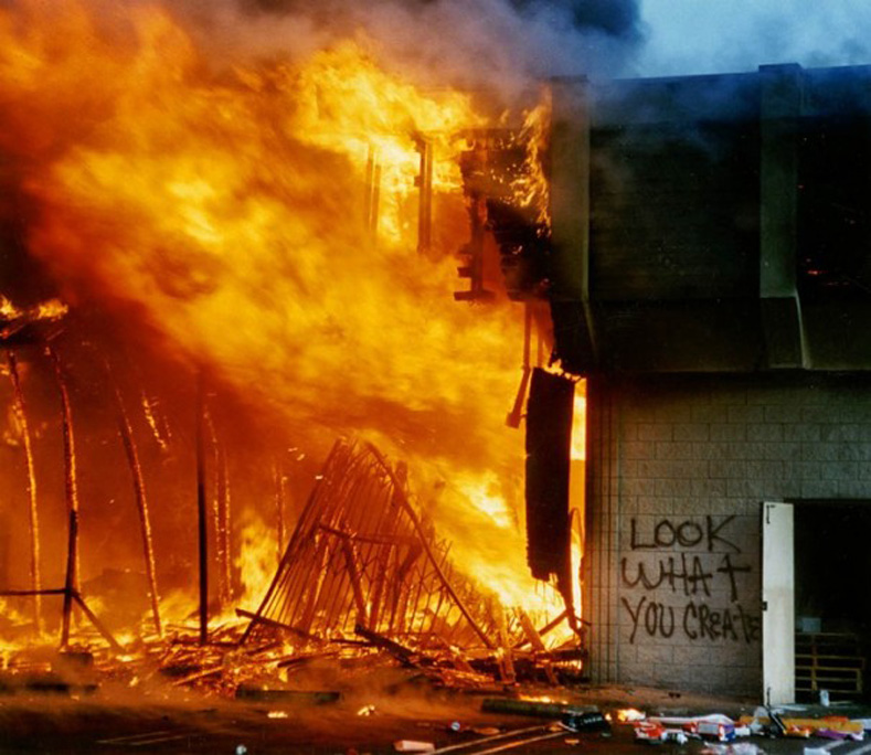 A shopping center at the corner of La Brea and Pico engulfed in flames.