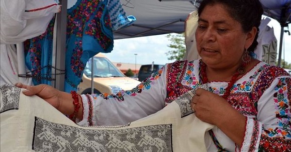 Constanza Garcia Lopez, an Indigenous mother of Oaxaca, shows a traditional huipil dress embroidered by other Indigenous women.