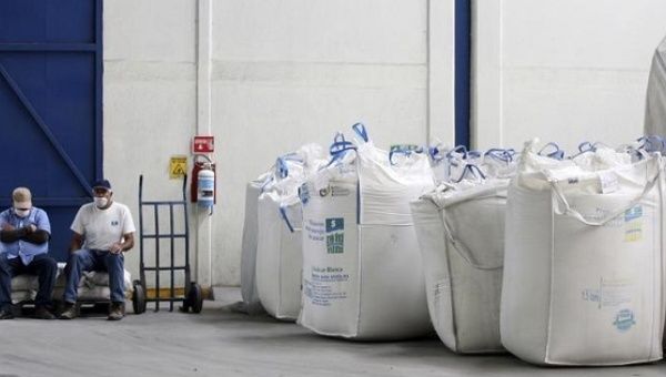 Mexican workers sit next to bags containing sugar at the San Francisco Ameca sugar factory in the town of Ameca, Jalisco, Feb. 18, 2011.