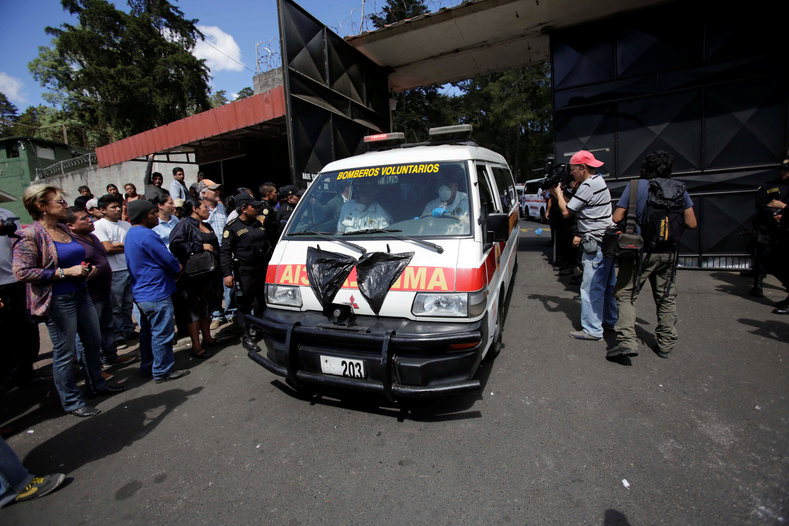 An ambulance carrying the bodies of those killed in the fire exits the Virgen de Asuncion home.