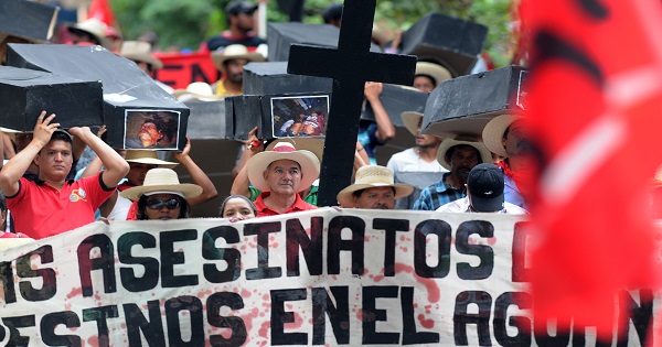 Members of the Peasant Unified Movement of Bajo Aguan in Honduras, carry mock coffins bearing pictures of community members killed in land conflict clashes.