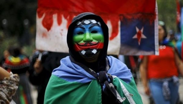 An Indigenous Mapuche activist wears a Guy Fawkes mask painted with the Mapuche flag during a protest march by Mapuche Indian activists against Columbus Day in downtown Santiago, Chile, October 12, 2015.
