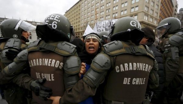 Mapuche activists try to get through riot police during a demonstration in Santiago, Chile Aug. 27, 2015, after truckers from the south arrived in the city.