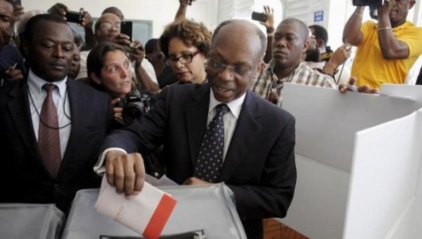 File photo from 2015 depicting Aristide dropping his ballot in an electoral bin at a polling station in Port-au-Prince.