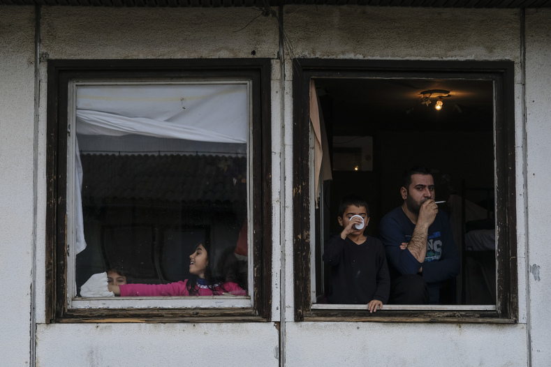 A family looks out the window of their bedroom in the refugee center where both Otra al-Khadra and Aras Mahmoud live in Belgrade.