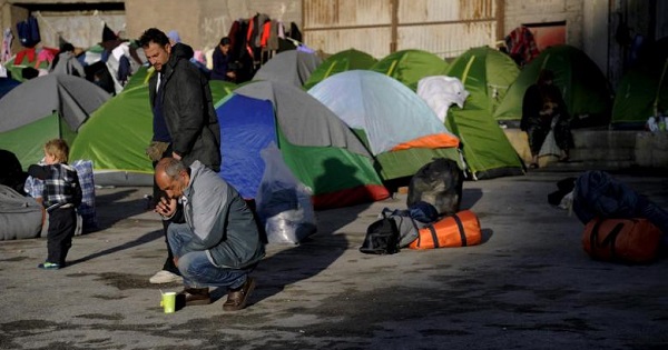 Refugees and migrants are seen by their tents, next to an old building at the port of Piraeus, near Athens, Greece.
