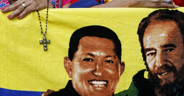 A supporter holds a crucifix next to a flag of Hugo Chavez (L) with Fidel Castro (R) in Caracas Jan. 5, 2013