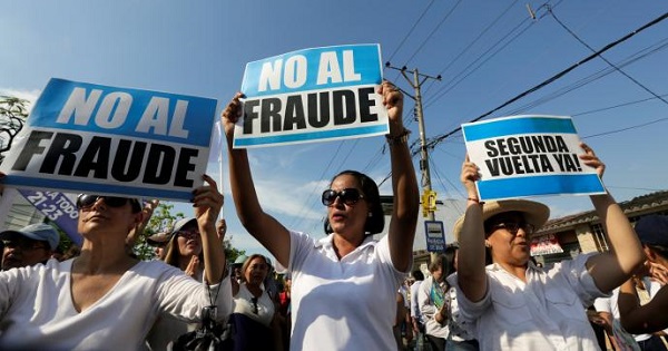 People hold signs reading 'No to fraud' and '(Election) Run-off now' as they protest near the electoral council in Guayaquil, Ecuador Feb. 20, 2017.