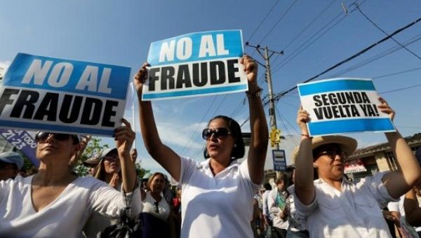 People hold signs reading 'No to fraud' and '(Election) Run-off now' as they protest near the electoral council in Guayaquil, Ecuador Feb. 20, 2017.