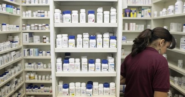 A pharmacy employee looks for medication as she works to fill a prescription while working at a pharmacy in New York.