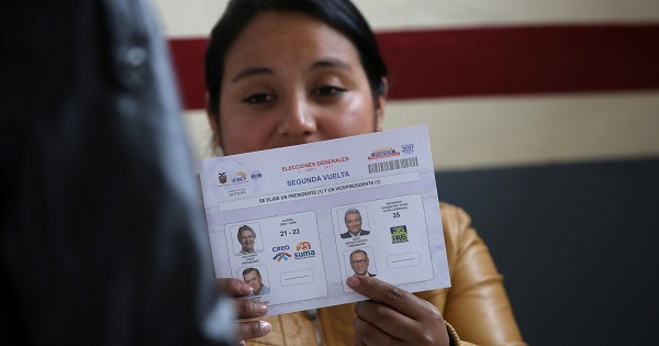 An electoral worker holds up a ballot paper at a polling station during the presidential election in Quito.