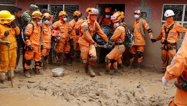 Rescue members recover a body in a house after flooding and mudslides caused by heavy rains pushed sediment and rocks into buildings in Mocoa, Colombia.