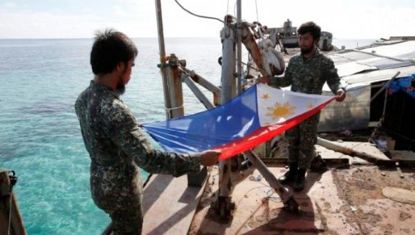Philippine Marines fold a Philippine national flag during a flag retreat on a marooned transport ship in the disputed Second Thomas Shoal, March 29, 2014.