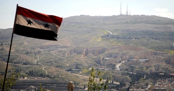 A Syrian national flag flutters as Qasioun mountain is seen in the background from Damascus, Syria April 7, 2017.